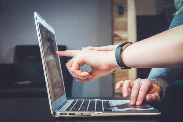 person pointing at laptop